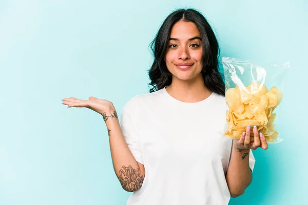 Junge Hispanische Frau Mit Einer Tüte Chips Auf Blauem Hintergrund — Stockfoto