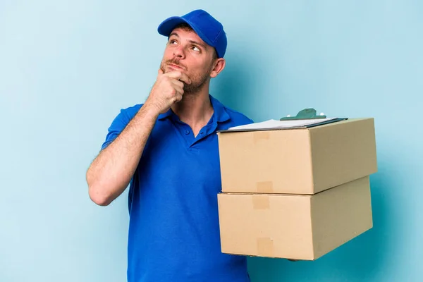 Young Caucasian Delivery Man Isolated Blue Background Looking Sideways Doubtful — Foto de Stock