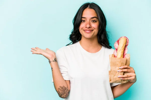 Ung Latinamerikansk Kvinna Äter Smörgås Isolerad Blå Bakgrund Visar Kopia — Stockfoto