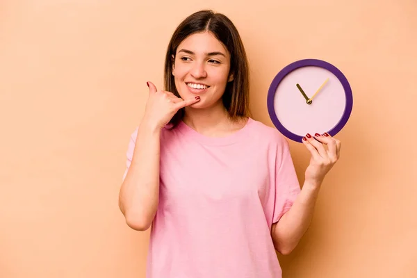 Ung Latinamerikansk Kvinna Håller Klocka Isolerad Beige Bakgrund Visar Mobiltelefon — Stockfoto