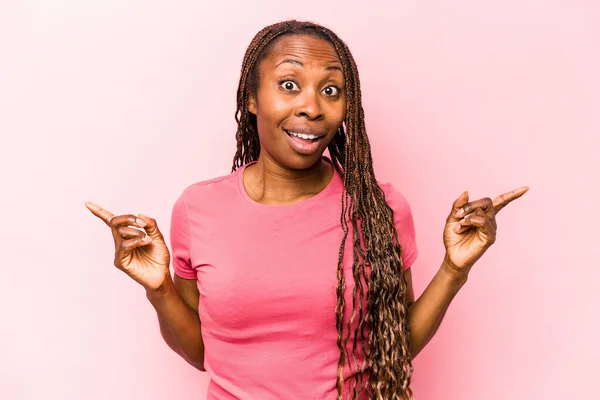 年轻的非洲裔美国妇女被隔离在粉红色的背景下 指向不同的复制空间 选择其中一个 用手指显示出来 — 图库照片