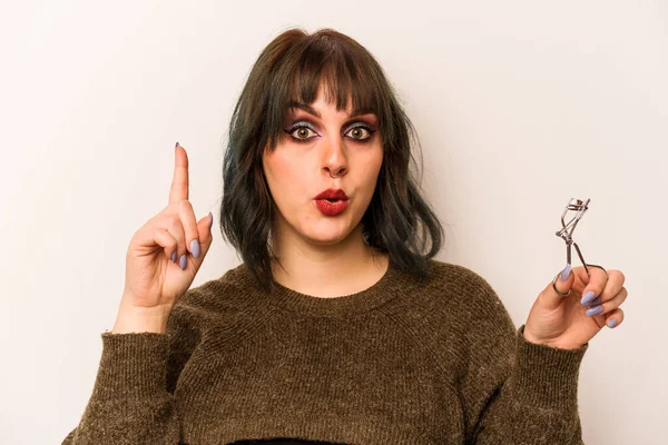 Beyaz arka planda kirpik bigudisi tutan genç beyaz makyajcı kadının harika bir fikri var, yaratıcılık kavramı..