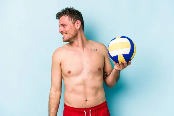 Young Caucasian Man Playing Volley Isolated Blue Background Looks Aside — Stok fotoğraf