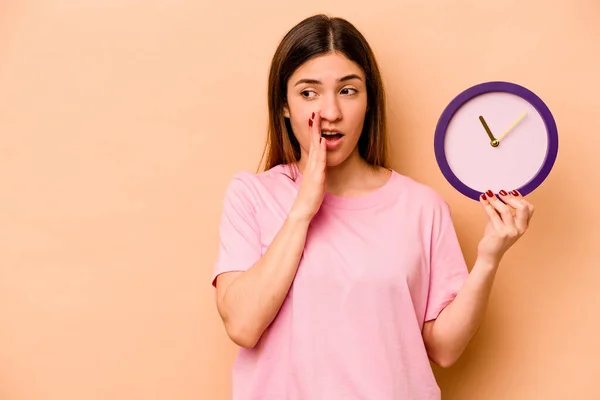 Mujer Hispana Joven Sosteniendo Reloj Aislado Sobre Fondo Beige Está — Foto de Stock