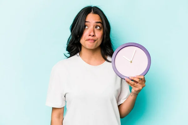 Young Hispanic Woman Holding Clock Isolated Blue Background Confused Feels — Stok fotoğraf