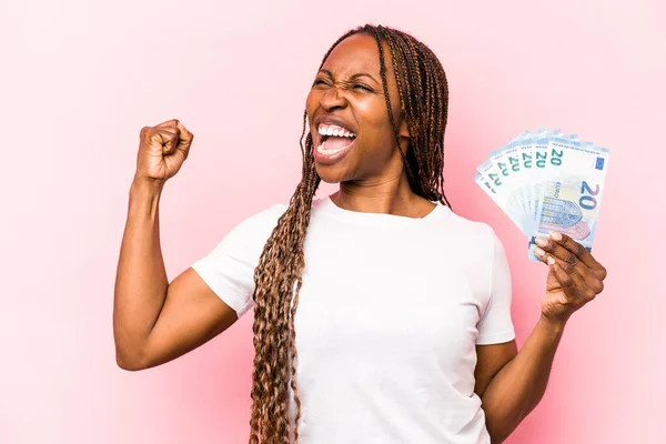 Молодая Афроамериканка Держит Банкноты Изолированы Розовом Фоне Поднимая Кулак После — стоковое фото
