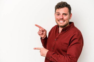 Beyaz arka planda izole edilmiş genç beyaz bir adam işaret parmağıyla fotokopi alanını işaret ederek şok oldu..