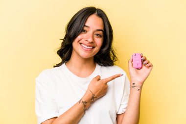 Anahtar taşıyan genç İspanyol kadın pembe arka plan noktalarında izole edilmiş, baş parmak uzakta, gülen ve kaygısız..