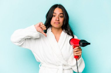 Mavi arka planda izole edilmiş kurutma makinesini tutan Latin kökenli genç bir kadın hoşlanmadığı bir hareket sergiliyor. Anlaşmazlık konsepti.