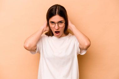 Genç İspanyol kadın bej arka planda izole edilmiş bağırıyor, çok heyecanlı, tutkulu, bir şeyden memnun..