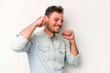 Beyaz arka planda izole genç beyaz adam özel bir günü kutluyor, atlıyor ve enerjiyle kollarını kaldırıyor..