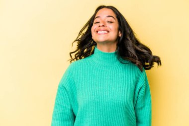 Sarı arka planda yalnız yaşayan genç İspanyol kadın dans ediyor ve eğleniyor..