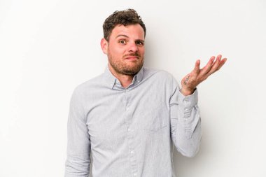 Beyaz arka planda izole edilmiş genç beyaz bir adam sorgulama sırasında omuz silkiyor ve şüphe duyuyor..