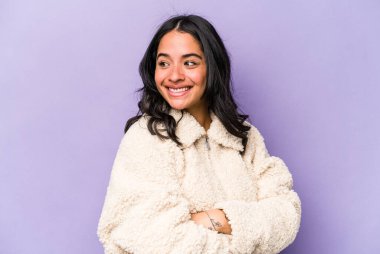 Mor arka planda izole edilmiş genç İspanyol kadın gülüyor ve eğleniyor..