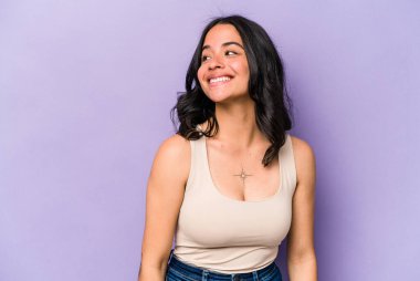 Mor arka planda izole edilmiş genç İspanyol kadın gevşemiş ve mutlu bir şekilde gülüyor, boynunda diş izleri var..