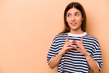 Latin kökenli genç bir kadın, bej arka planda izole edilmiş..