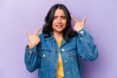 Mor arka planda izole edilmiş genç İspanyol kadın işaret parmağıyla bir hayal kırıklığı gösteriyor..