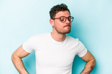 Kafkasyalı genç adam mavi arka planda izole edilmiş hedeflerine ve amaçlarına ulaşma hayali kuruyor.