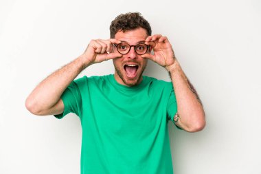 Beyaz arka planda izole edilmiş genç beyaz bir adam bir başarı fırsatı bulmak için gözlerini açık tutuyor..