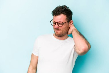 Kafkasyalı genç adam mavi arka planda izole edilmiş. Yorgun ve uykulu. Elini başının üstünde tutuyor..