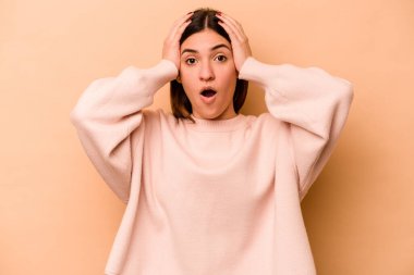 Latin kökenli genç bir kadın, bej arka planda izole edilmiş şok geçiriyordu. Önemli bir buluşmayı hatırladı..