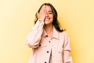 Sarı arka planda izole edilmiş genç İspanyol kadın yüzünün yarısını palmiye ile örterek eğleniyor..