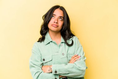 Sarı arka planda izole edilmiş genç İspanyol kadın tekrarlanan bir görevden yoruldu..