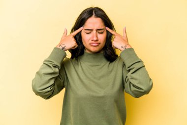 Sarı arka planda izole edilmiş genç İspanyol kadın bir işe odaklanmış, işaret parmaklarını işaret ediyor..