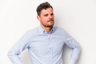 Beyaz arka planda izole edilmiş, hoşnutsuzca kaşlarını çatmış, kollarını kavuşturmuş genç beyaz bir adam..