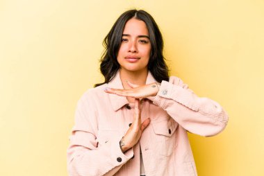 Sarı arka planda izole edilmiş genç İspanyol kadın bir mola hareketi gösteriyor..