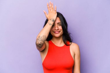 Mor arka planda izole edilmiş genç İspanyol kadın bir şeyi unutuyor. Alnına avuç içi ile vuruyor ve gözlerini kapıyor..