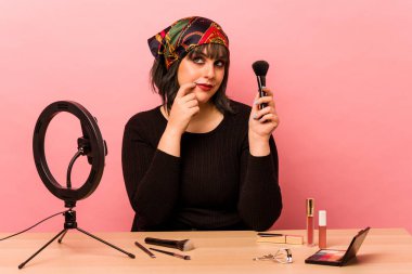 Makyaj sanatçısı genç bir kadın pembe arka planda izole edilmiş makyaj dersi veriyor. Bir şeyin fotokopi odasına baktığını düşünüyor..