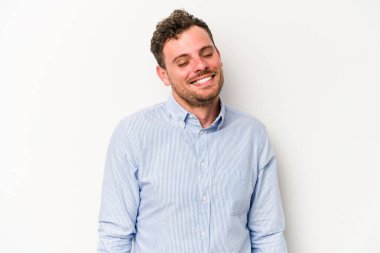 Beyaz arka planda izole edilmiş genç beyaz adam gülüyor ve gözlerini kapıyor, rahatlamış ve mutlu hissediyor..