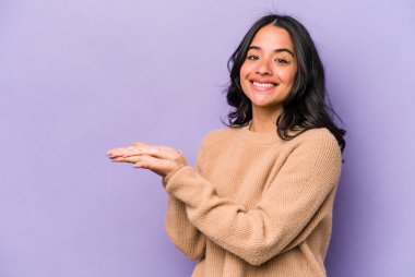 Mor arka planda izole edilmiş genç İspanyol kadın avucunun içinde bir kopya alanı tutuyor..