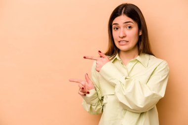 Bej arka planda izole edilmiş genç İspanyol kadın işaret parmağıyla fotokopi alanını işaret ederek şok oldu..