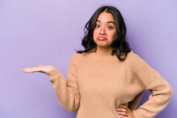 Mor arka planda izole edilmiş genç İspanyol kadın bir avuç içinde fotokopi alanı ve belinde bir el daha gösteriyor..