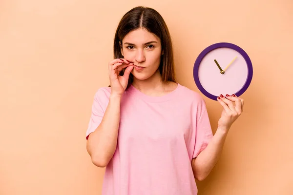 Mujer Hispana Joven Sosteniendo Reloj Aislado Sobre Fondo Beige Con — Foto de Stock