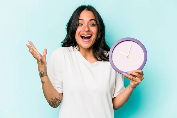 Young Hispanic Woman Holding Clock Isolated Blue Background Receiving Pleasant — Stok fotoğraf