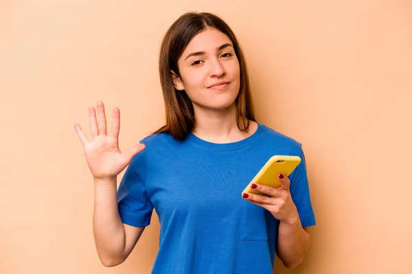 Ung Kaukasiska Kvinna Som Håller Mobiltelefon Isolerad Beige Bakgrund Ler — Stockfoto