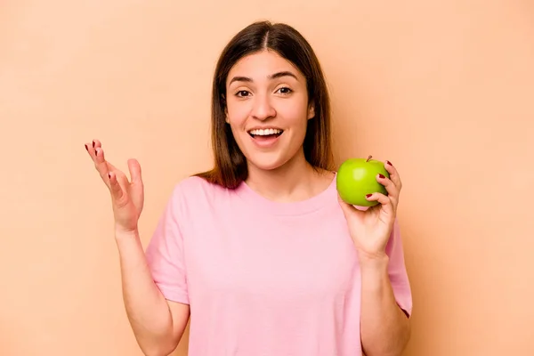 Young Hispanic Woman Holding Apple Isolated Beige Background Receiving Pleasant — Stock Photo, Image