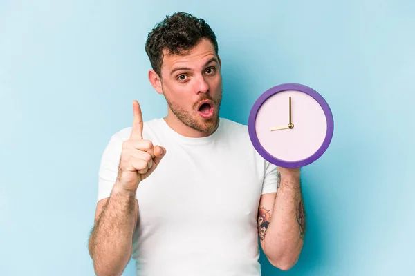 Young Caucasian Man Holding Clock Isolated Blue Background Having Idea — Stock Fotó