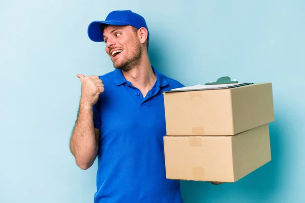 Young Caucasian Delivery Man Isolated Blue Background Points Thumb Finger — Stockfoto