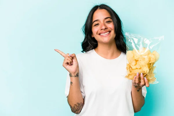 Ung Latinamerikansk Kvinna Håller Påse Chips Isolerad Blå Bakgrund Ler — Stockfoto