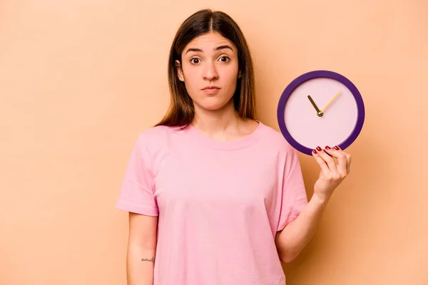 Jeune Femme Hispanique Tenant Une Horloge Isolée Sur Fond Beige — Photo