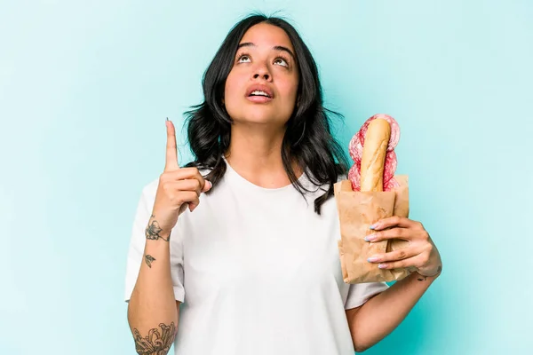 Ung Latinamerikansk Kvinna Äter Smörgås Isolerad Blå Bakgrund Pekar Upp — Stockfoto