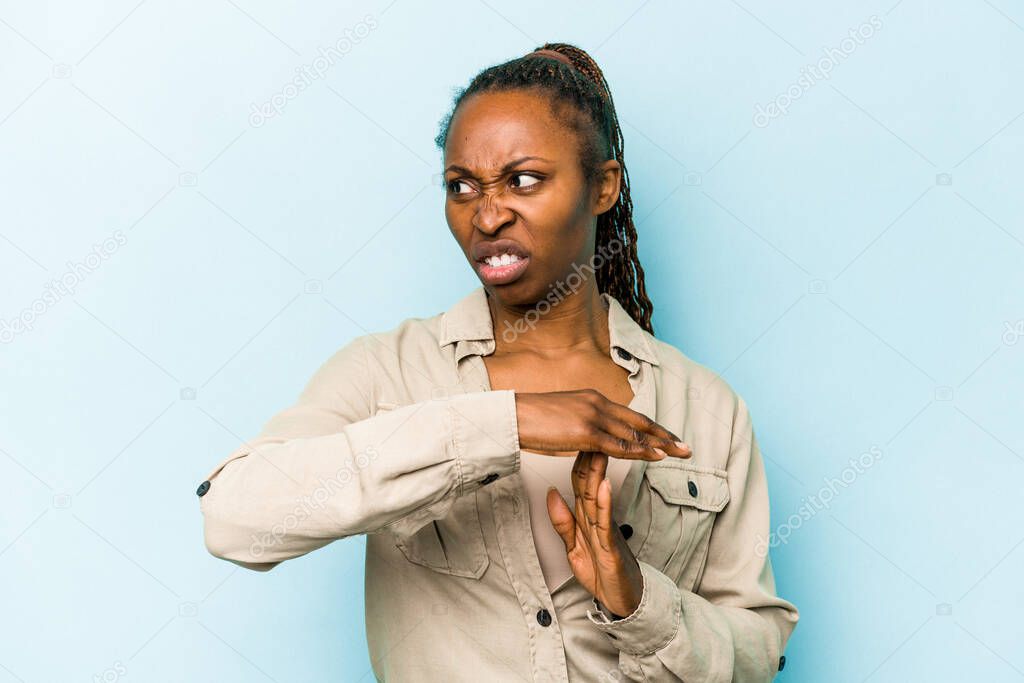 Young african american woman isolated on blue background showing a timeout gesture.