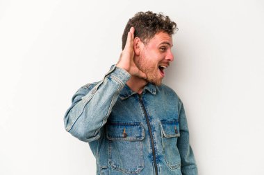 Beyaz arka planda izole edilmiş genç beyaz adam bir dedikoduyu dinlemeye çalışıyor..