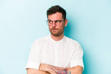 Mavi arka planda izole edilmiş genç beyaz adam tekrarlanan bir görevden yoruldu..