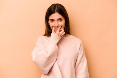 Latin kökenli genç bir kadın bej arka planda izole edilmiş. İki seçenek arasında şüphe duyuyor..