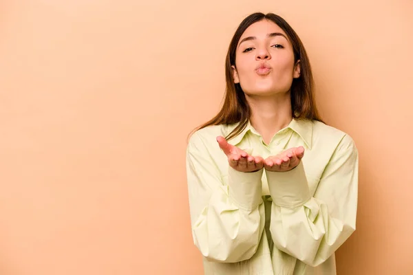 年轻的惊慌失措的女人在米色的背景下 双唇紧闭 手牵着手心送出空气之吻 — 图库照片